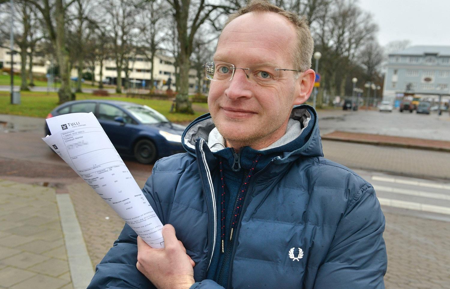 En man står utomhus med en räkning.