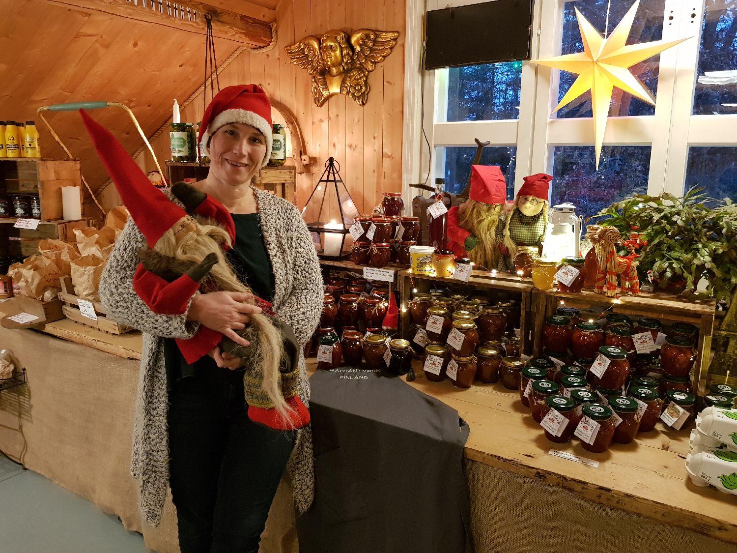 Dam med en tomte i famnen i en välfylld, julig, julbod