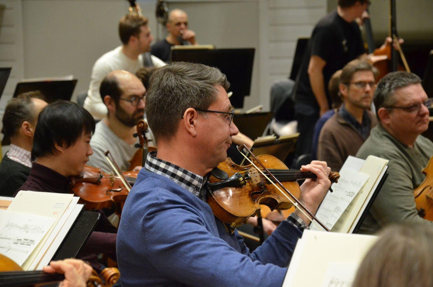 Man som spelar violin i en orkester.