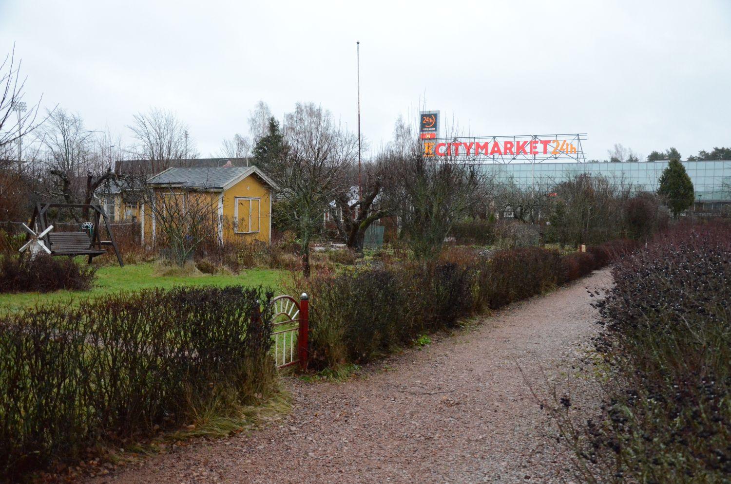 Ett litet hus med port och häck. I bakgrunden Citymarkets skylt.