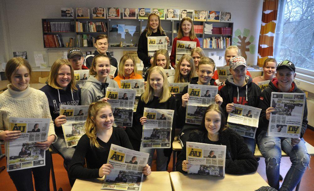 klass i ett klassrum. Alla har en ÅU-tidning i handen