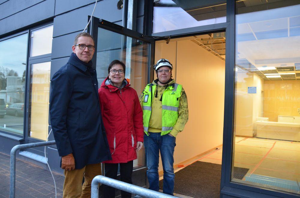 Tre personer vid en ingång till ett hus.