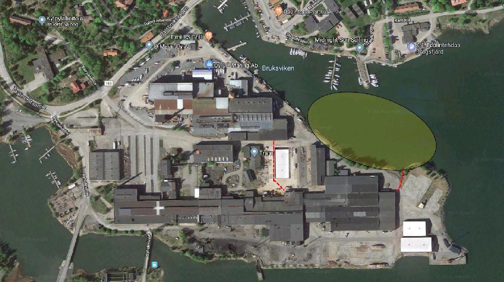 Flygfoto av ett industriområde med stora byggnader. I viken intill är ett stort område färgat i grönt