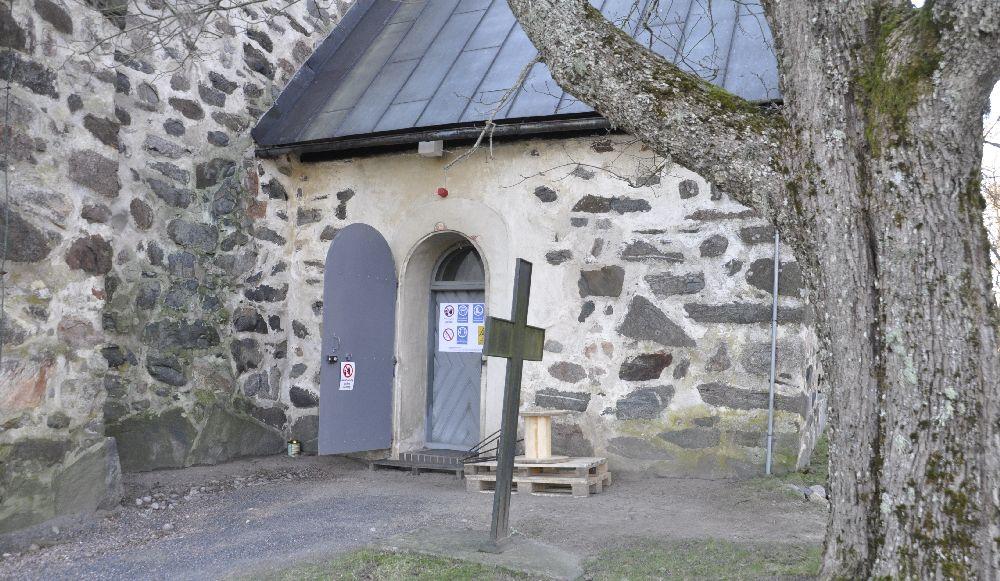 Sidoingång till kyrka försedd med varningsplakat