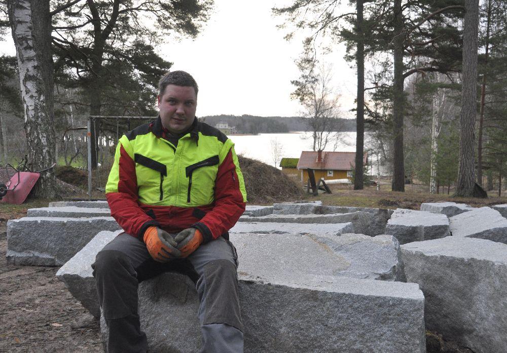 Man i arbetskläder sitter på granitblock.