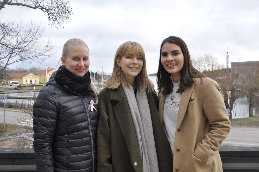 Tre damer på en balkong med utsikt över en hamnbassäng