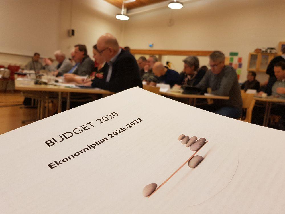 Budgetbok i förgrunden. Fuöömäktigeskara i bakgrunden.