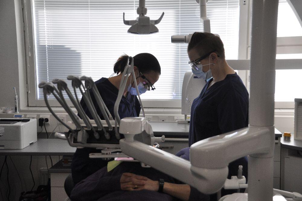 Två tandvårdare behandlar en patient i en tandläkarstol
