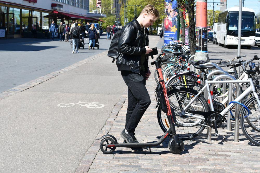 Ung mananvända en elsparkcykel. står i beråd att