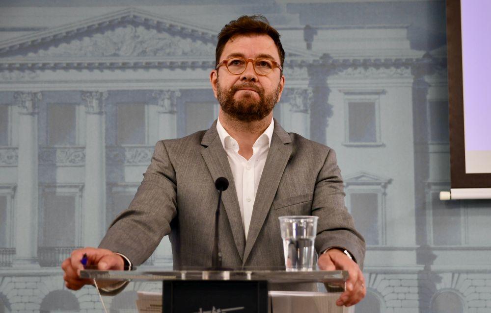 Man med glasögon står vid ett podium.