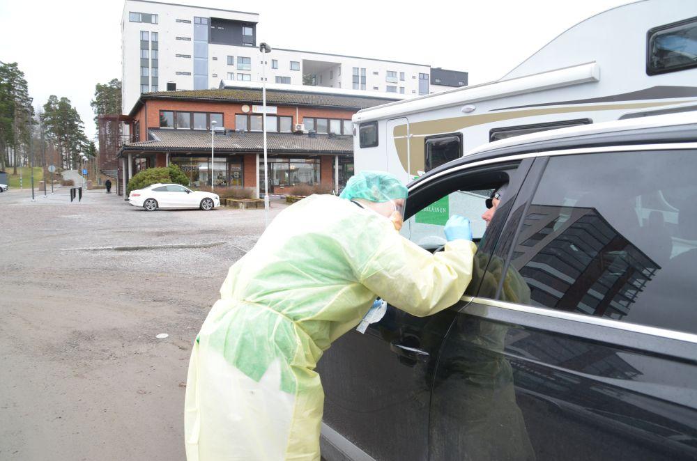 Laboratorieskötare i skyddsutrustning testar en kund som sitter i en bil.