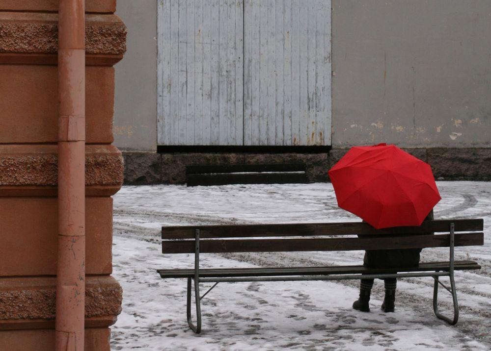 Människa sitter på parkbänk på vintrig innergård