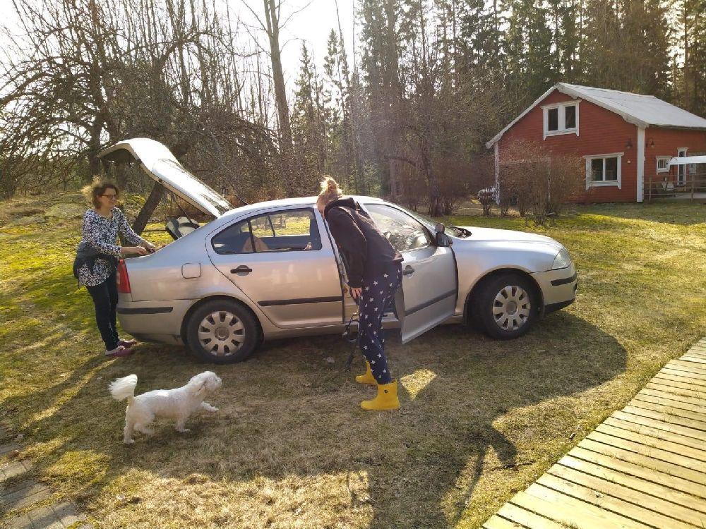 Bil packas. Två personer och en liten hund syns på bilden