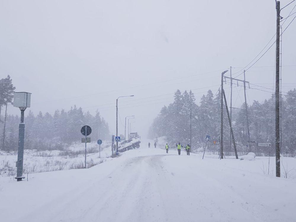 Snöig väg med ett stort fordon i diket.