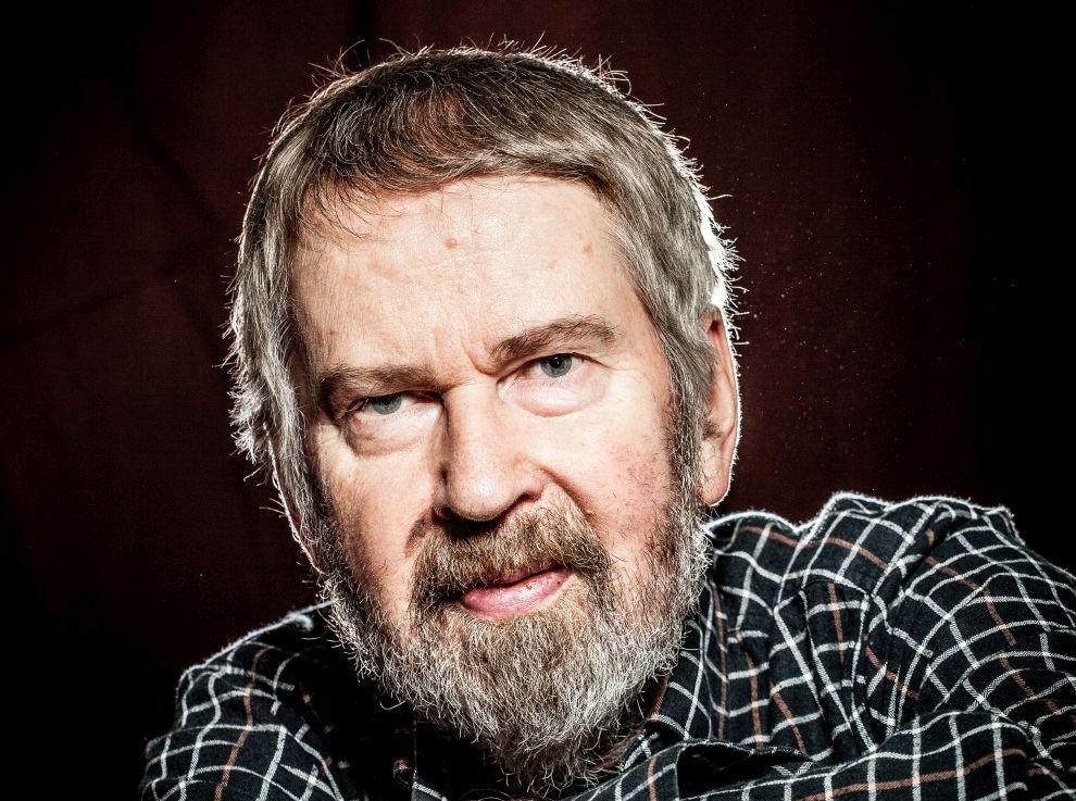 författarporträtt av en man med rutig skjorta