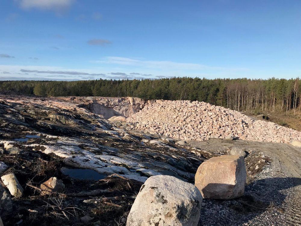 Dagbrott. Högar med rödaktig sten synd.