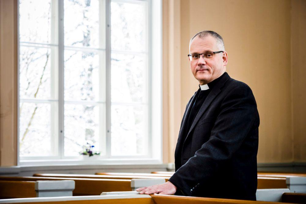 Präst står vid kyrkfönster