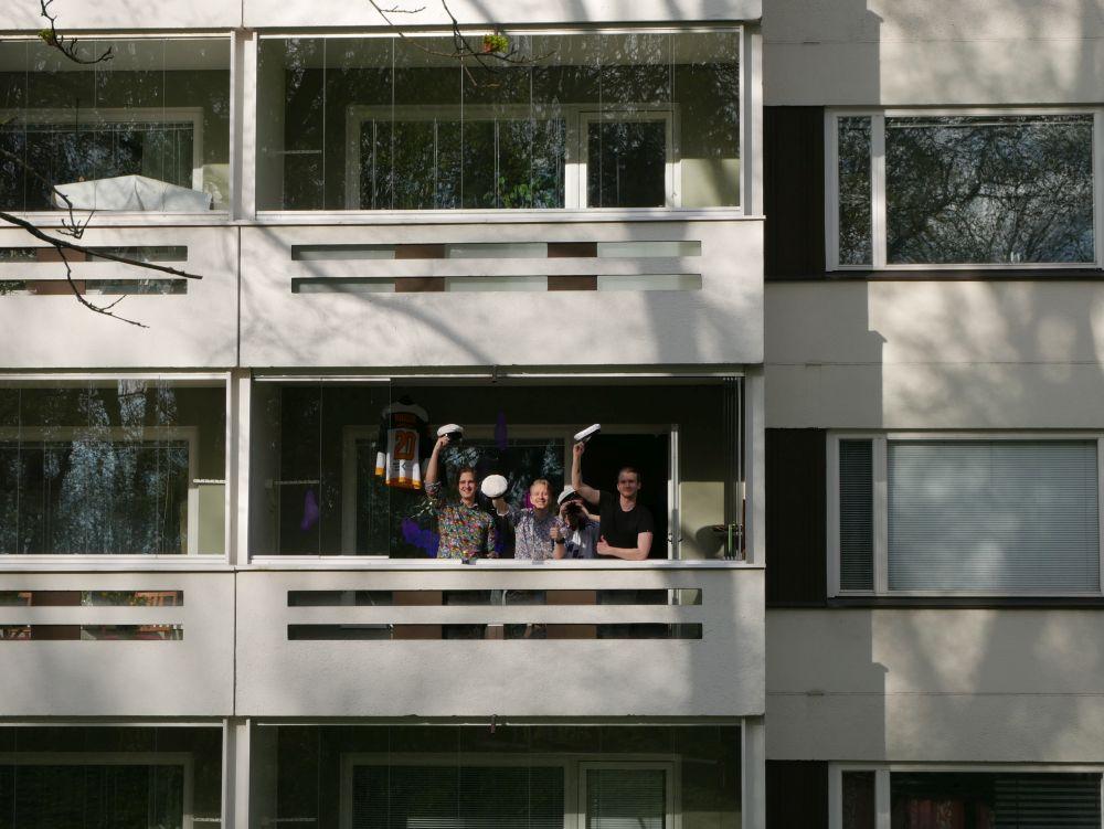 Fyra män viftar med studentmössor från en balkong