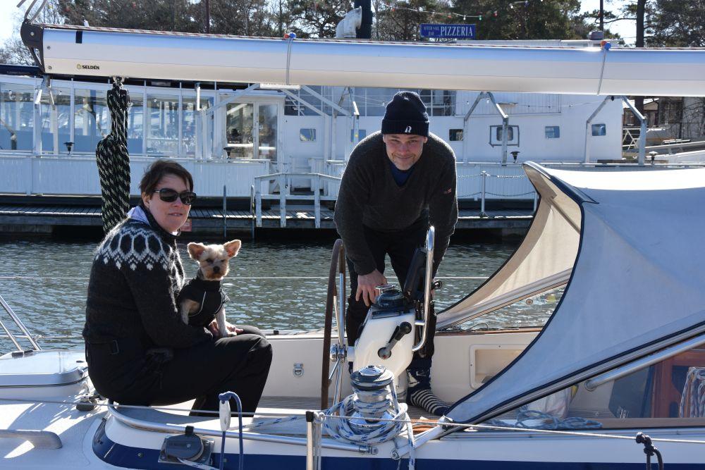 En kvinna, en man och en liten hund på en segelbåt.