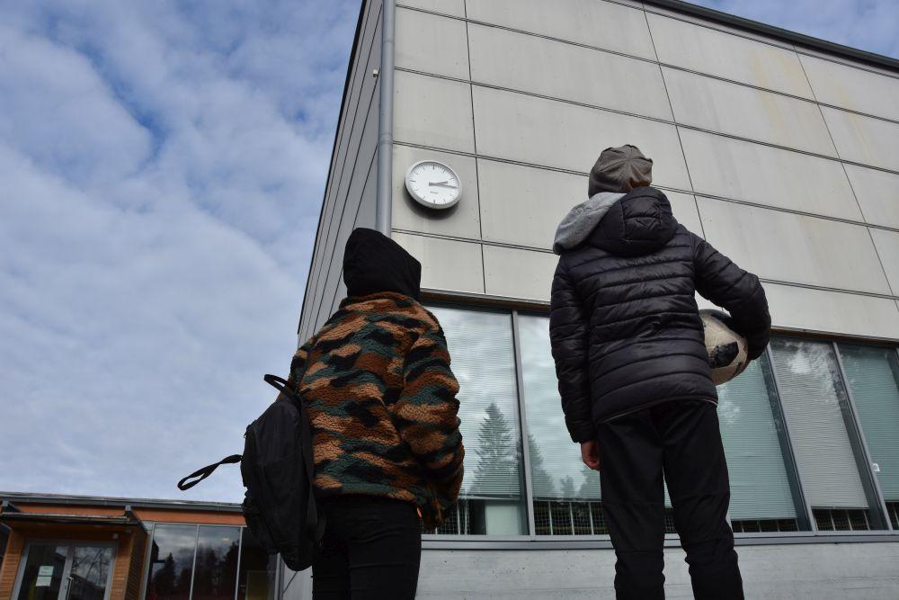Två barn utanför en skolbyggnad.