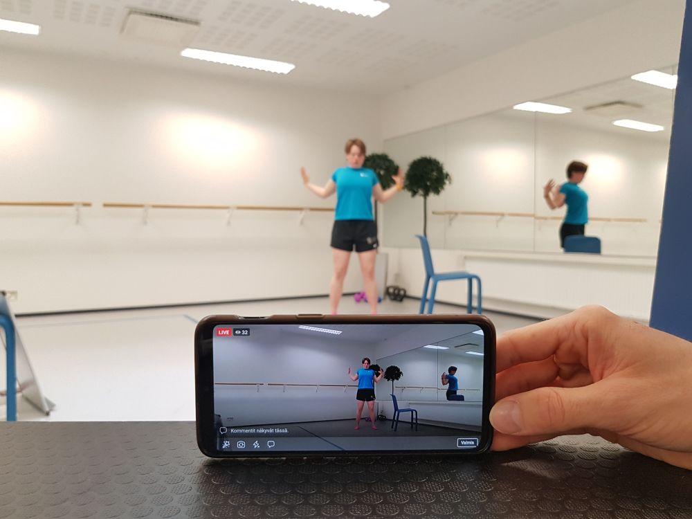 Ung kvinna tränar framför en mobiltelefon som filmar.