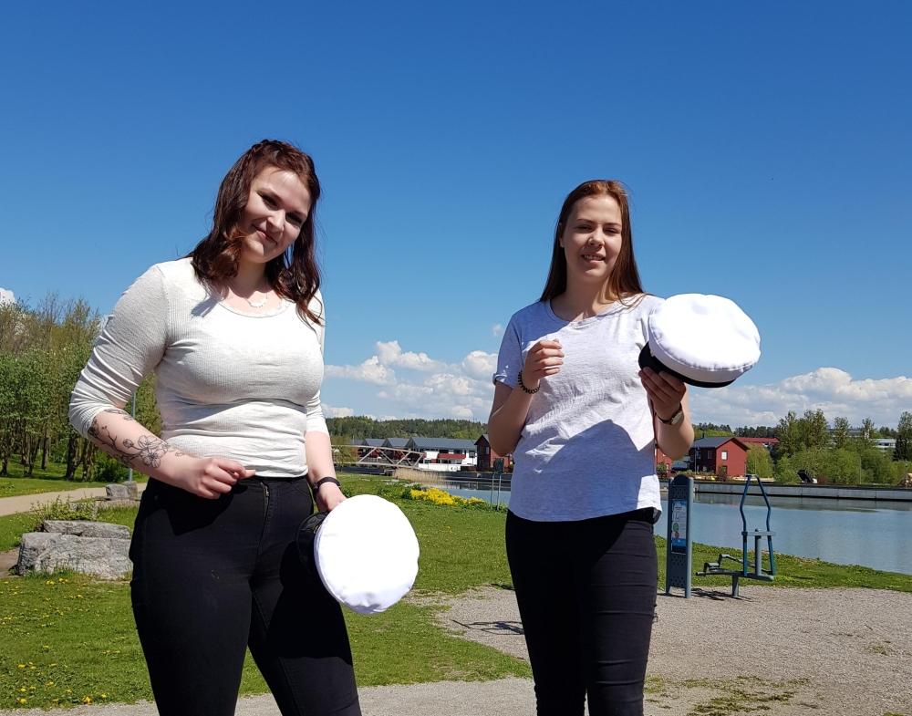 två flickor håller i studentmössor