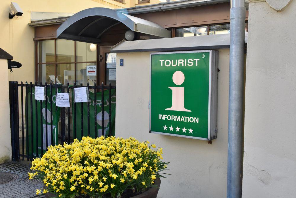 Ingången till en turistinformation med en gul blomma och en grön skylt med texten "turist information".