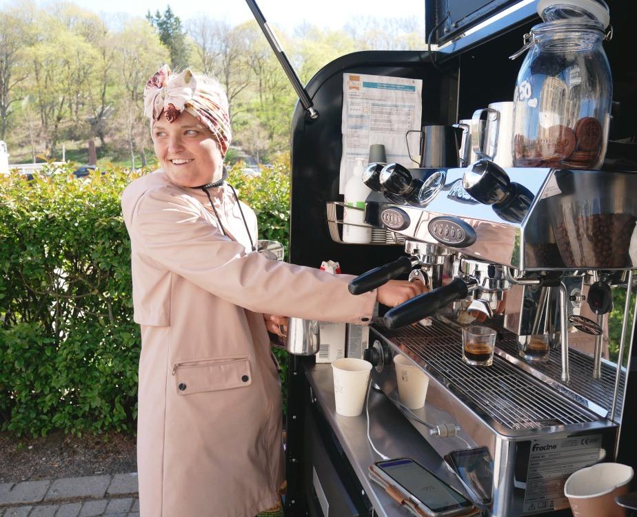 dam i ljusröd rock serverar kaffe ur kaffemaskin installerad i svart moped