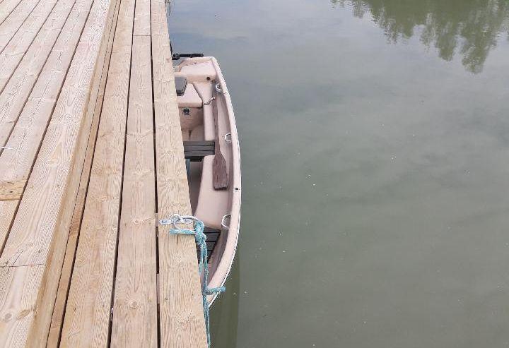 En roddbåt som ligger halvt under en brygga.