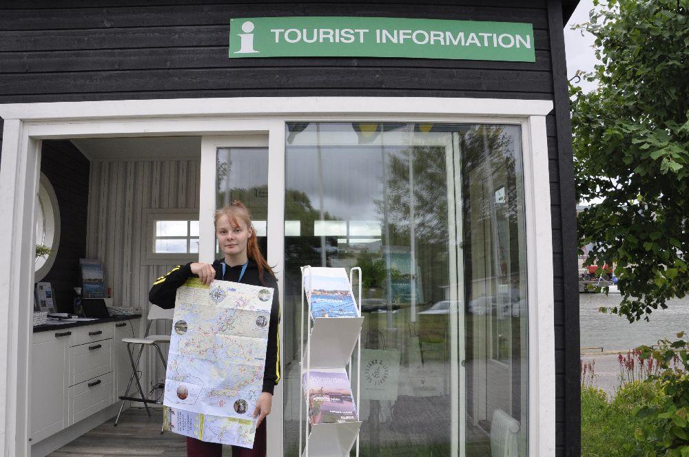 Ung dam utanför infokiosk med en stor karta i handen.