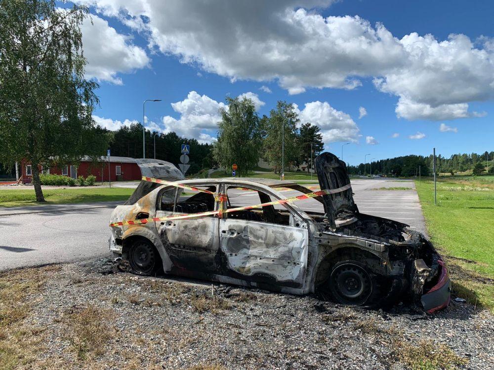 En brunnen bil inlindad i varningstejp på en annars tom parkeringsplats.