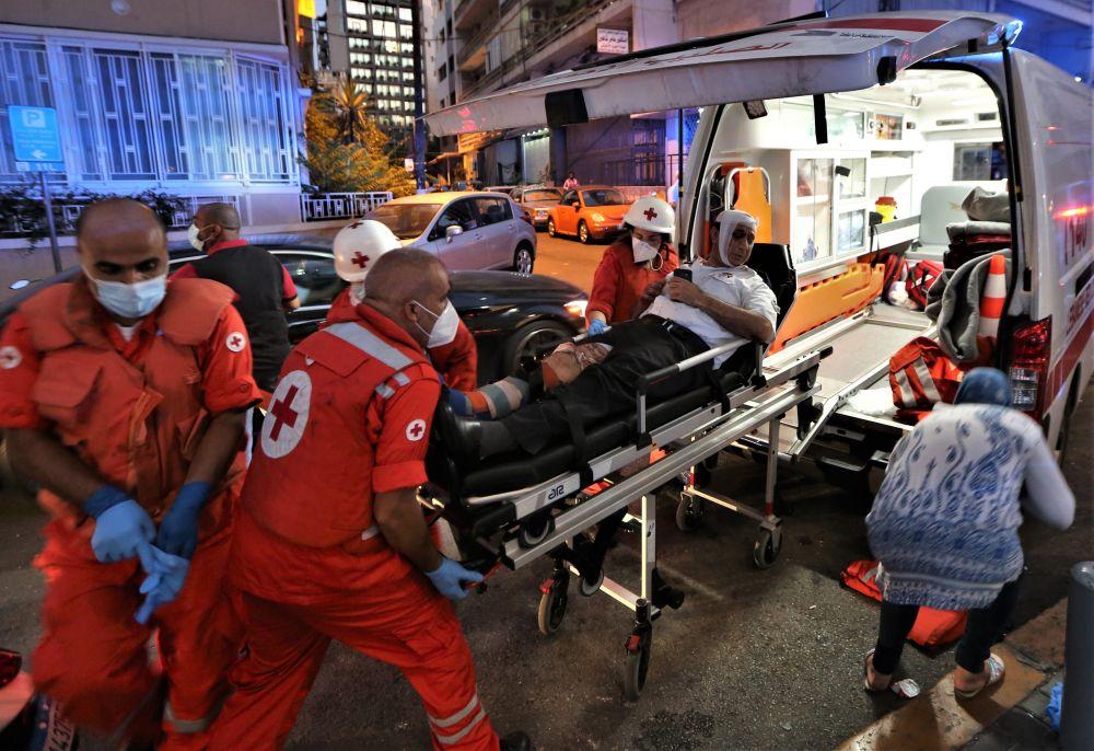 Personal från Röda Korset hjälper en skadad man in i en ambulans.