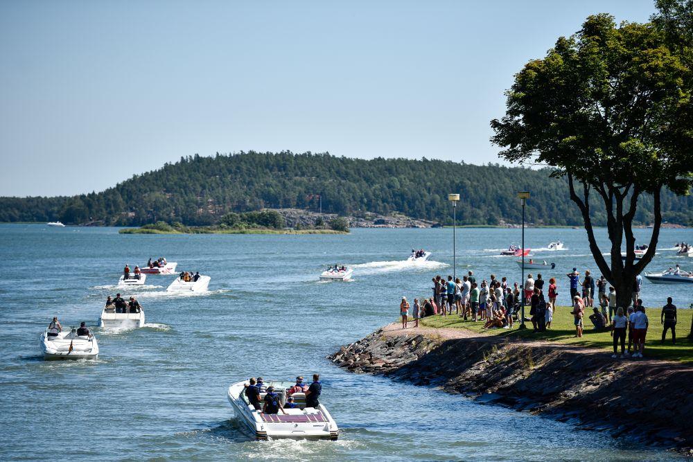 Flera båtar kör i rad efter varandra runt en udde